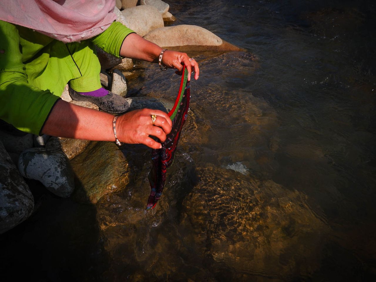 Razia washes her menstrual cloth in a stream near her tent in Chandipora area on the outskirts of Srinagar. Date: 27 April, 2022.