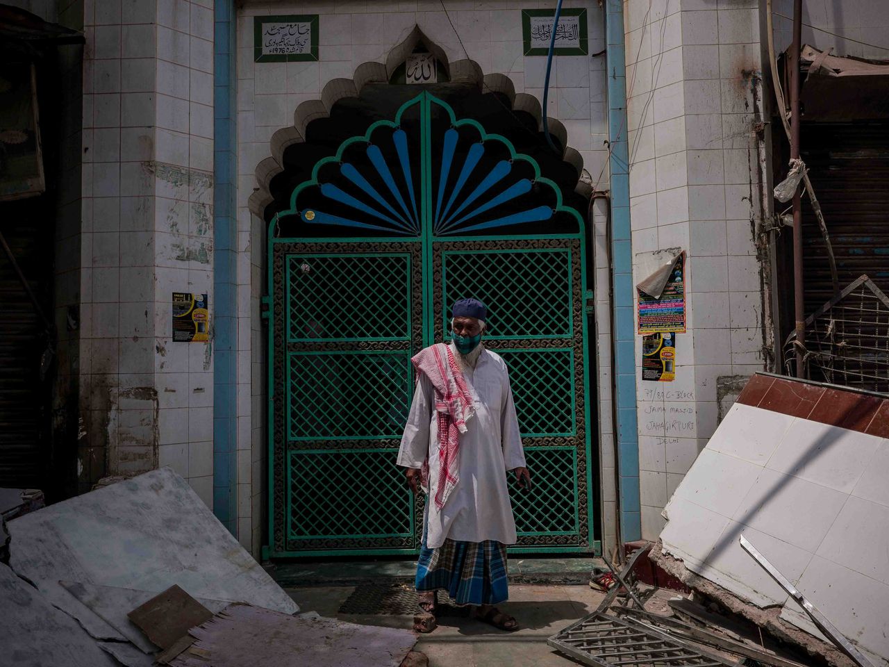 A Muslim man stands in front of the gate of the mosque which is said to be the epicentre of the clashes between two communities after earthmovers razed the structures claimed as encroachment by civic authorities outside the mosque at the clash affected spot in Jahangir Puri in New Delhi on April 20, 2022. Bulldozers continued razing property for nearly two hours after India's chief justice issued an order to halt.
