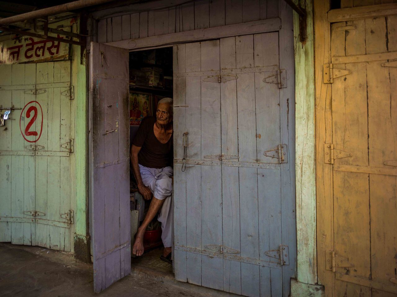A shopkeeper in Khargone, India, peers out of his shop on April 15, 2022, a few days after the unrest. The authorities had imposed a curfew, and he was waiting for it to be relaxed so he could open for business.